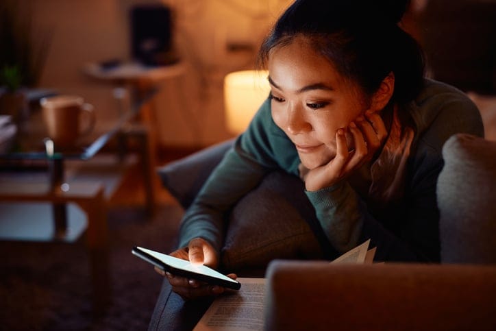 woman texting on couch at night