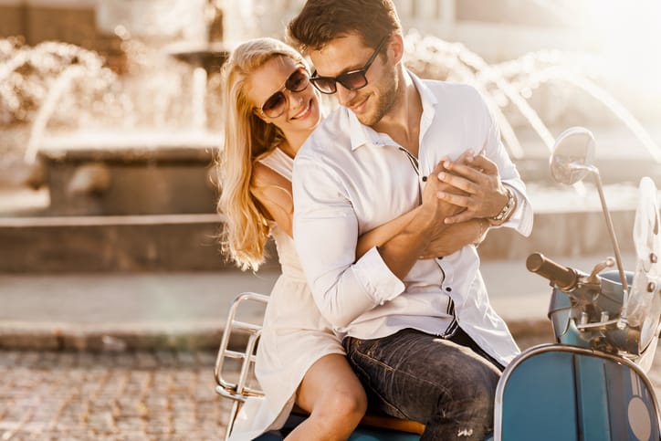Young happy couple sitting on scooter