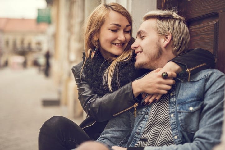 Smiling couple embracing outdoors and talking to each other.