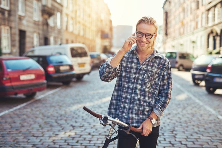 Happy young man in the city, talking on his cellphone while smiling