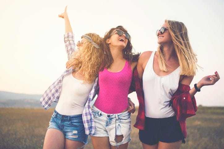 Three beautiful girls holding together, enjoying a carefree summer day outdoors.
