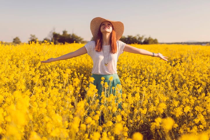 Young woman standing in the middle of the flower meadow.