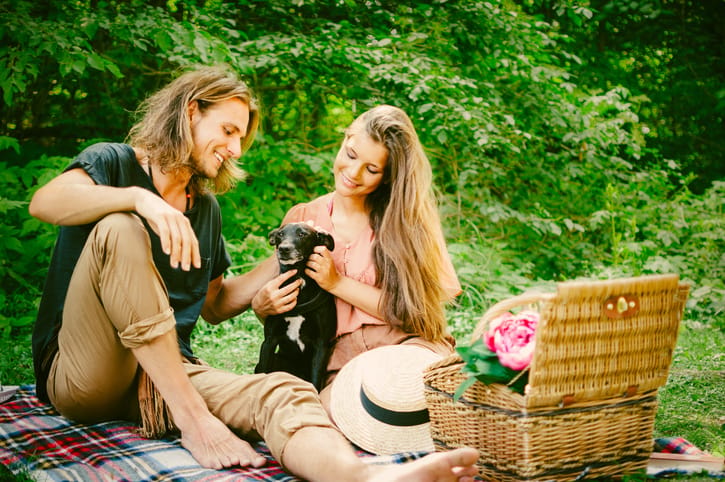 Young couple picnicking in the park with their dog.