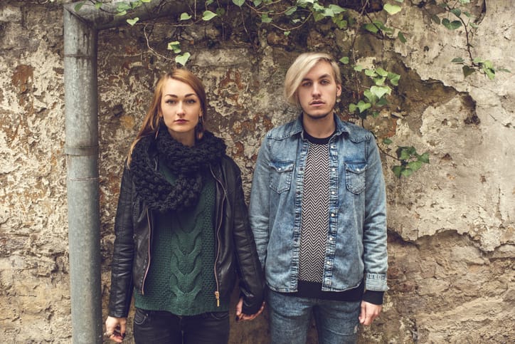young hipsters standing against wall