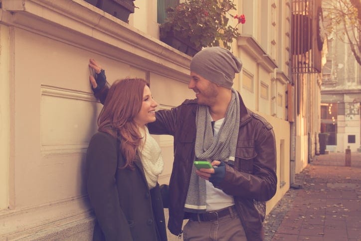 Couple in love using cellphone outdoors.