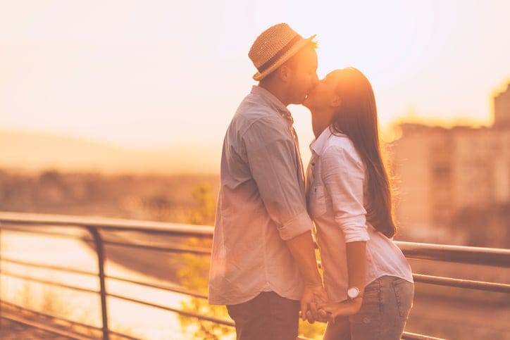 Backlit portrait of a young romantic couple at sunset outdoors, enjoying their time together.