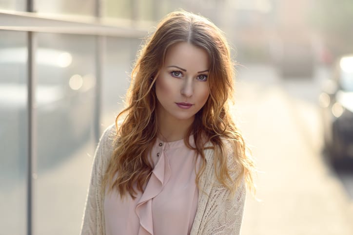Beautiful young serious woman looking at camera in early morning sunlight outdoors