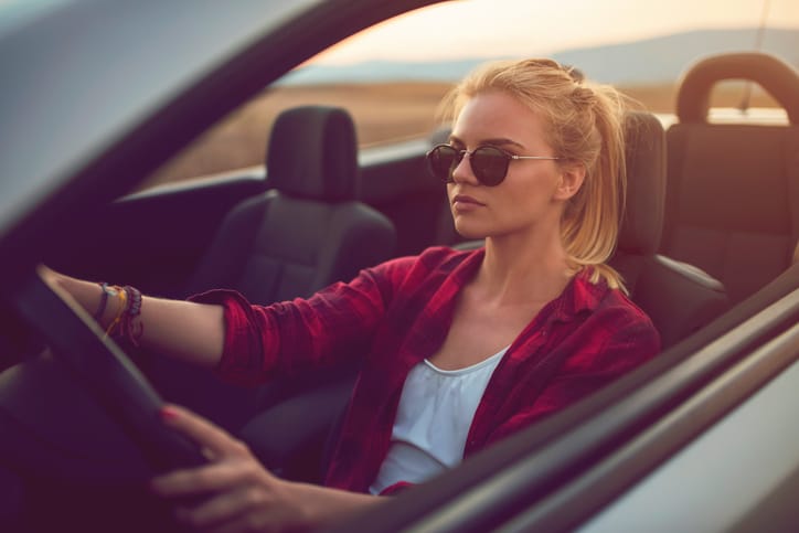 Beautiful young woman with sunglasses driving a cabrio.