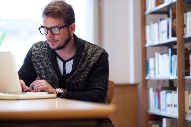 Young man on his computer in the library.
