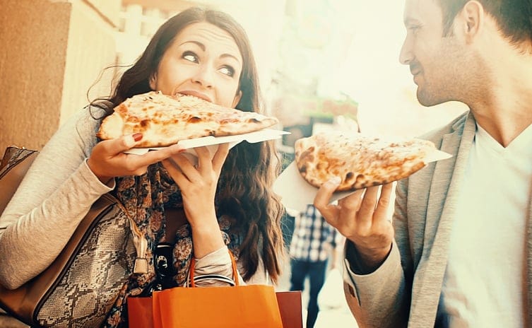 Couple eating pizza while walking.