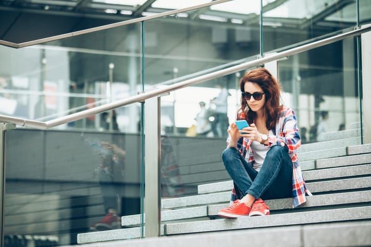 Young woman using smart phone on stairs