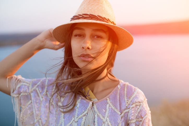 Close up face of beautiful latin trendy woman wearing a stylish hat with lens flare