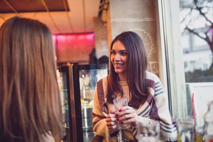 Two friends sitting in the cafe ,having something to drink , and talking