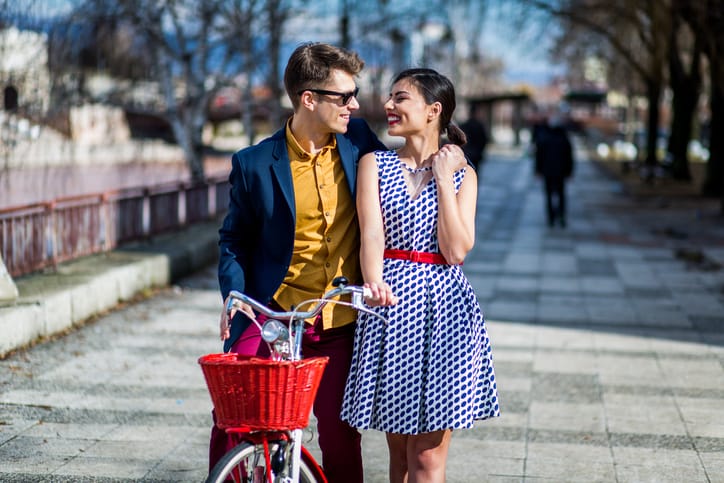 Young beautiful couple walking through the city with bike on a beautiful sunny spring day