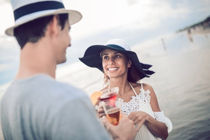 Happy Romantic Couple Drinking Cocktail by the Sea