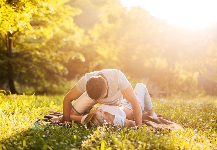 Young loving couple relaxing in grass during spring day and communicating.