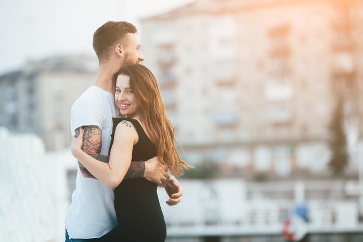 couple posing against the backdrop of the city by the lake