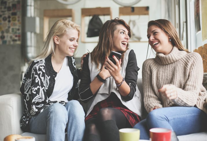 Friends using smart phone together at home.