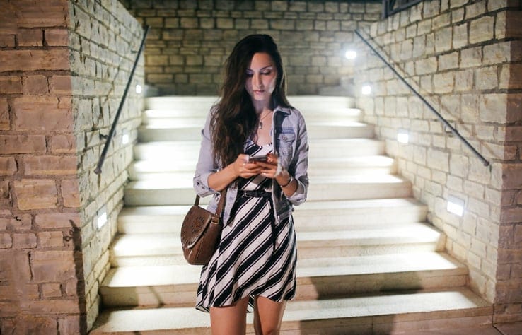 Vintage toned image of a young, single woman, walking in the evening in front of her apartment in the Croatian town of Rovinj, in Istria. She is enjoying a warm summertime evening, wearing a casual dress and a small denim vest, going out for a drink with friends or maybe a date.