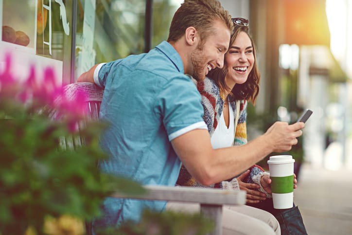 Shot of a happy young couple using a smartphone together while spending the day downtown