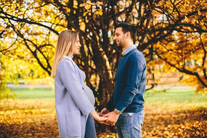 Pregnant woman and man relaxing in the autumn park