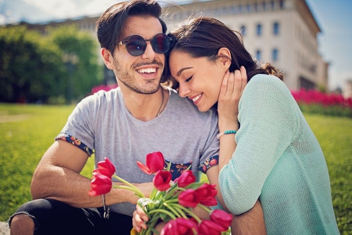Happy, young couple is sitting and hugging in the city park
