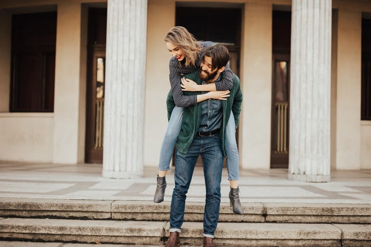 Bearded man giving his girfriend a piggyback ride