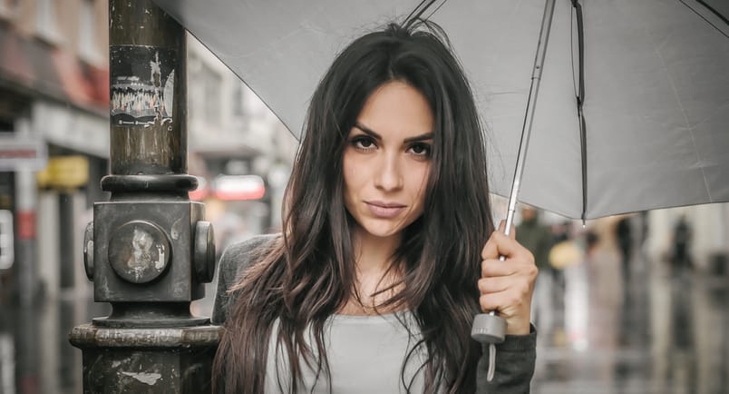 Portrait of young woman with an umbrella under rain on a city street