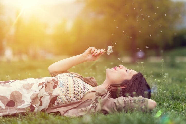 Relaxed woman in the park blowing dandelion