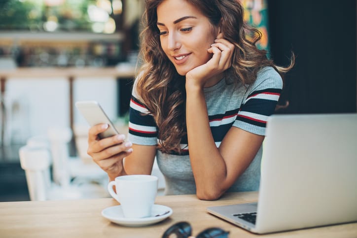 Young woman sitting in cafe looking at her mobile phone.