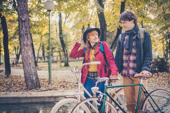 Young couple enjoying romantic ride with bicycle in autumn park