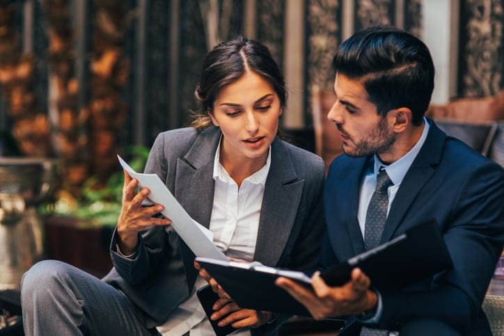 Two business people discussing a document in a meeting.
