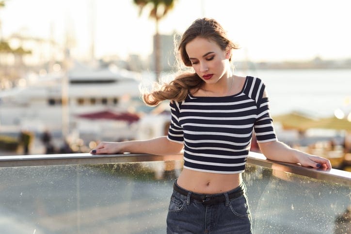 Blonde woman, model of fashion, sitting in urban background.