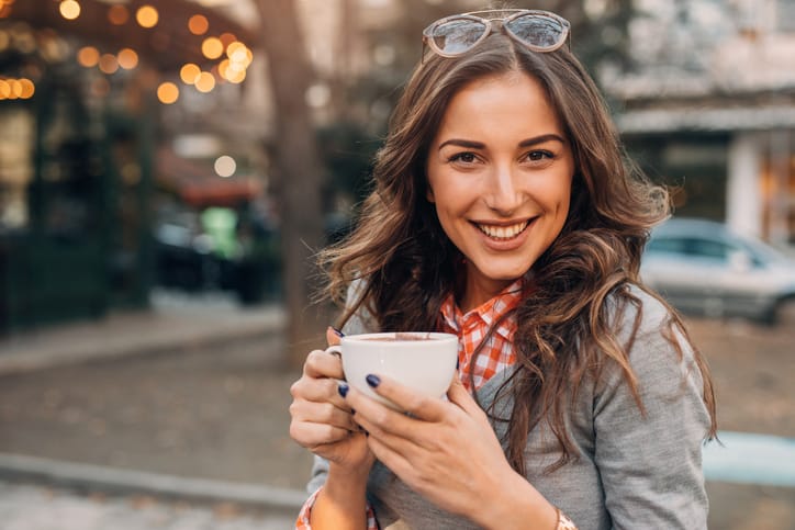 Young woman enjoying a cup of coffee at an outdoor cafe.