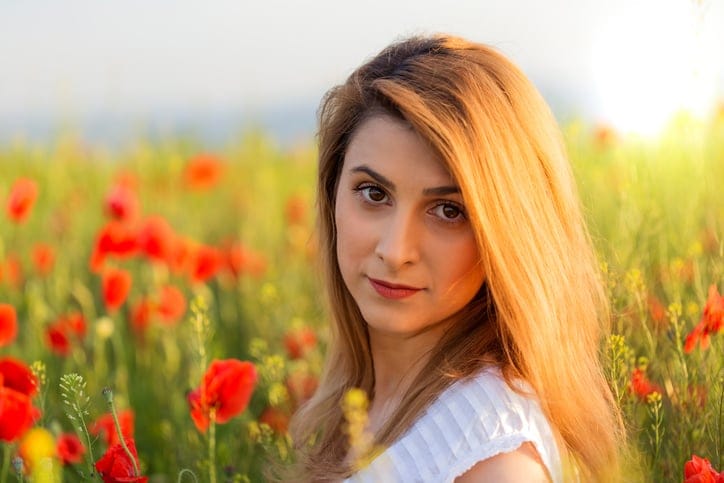 Portrait of blonde woman in white dress standing on the field