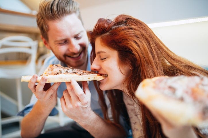 Couple sharing pizza and eating together happily