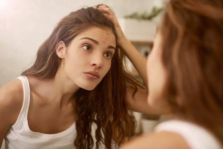 Beautiful, brown haired woman is looking to the mirror
