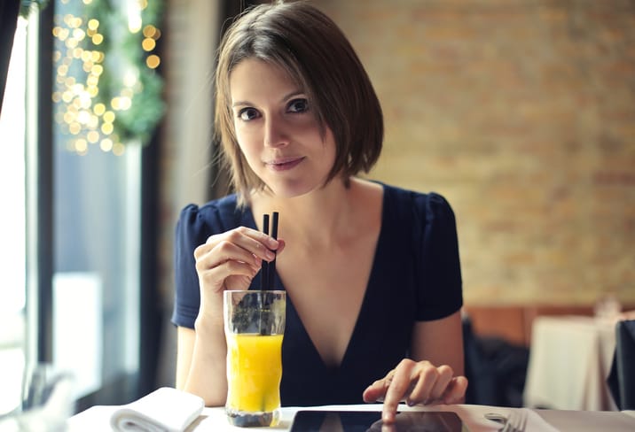 Portrait of a young woman who is drinking orange juice