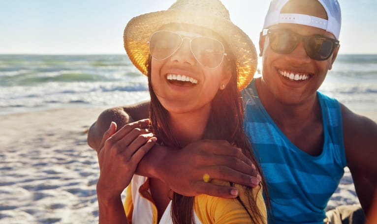 Portrait of a young couple sitting on the beach on a sunny day