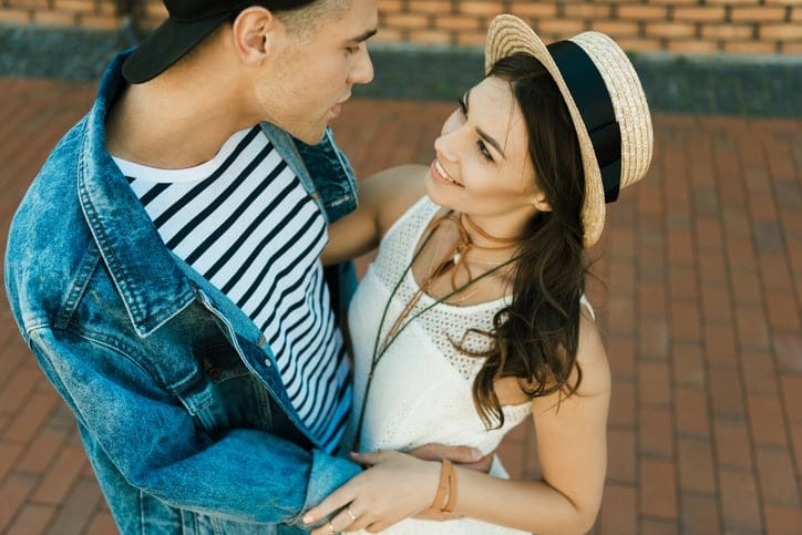 happy young hipster couple looking at each other and hugging on the street