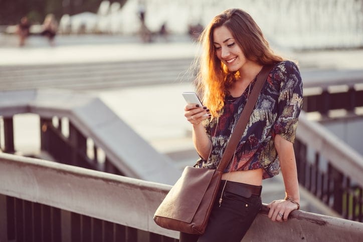 Smiling woman using phone in the city