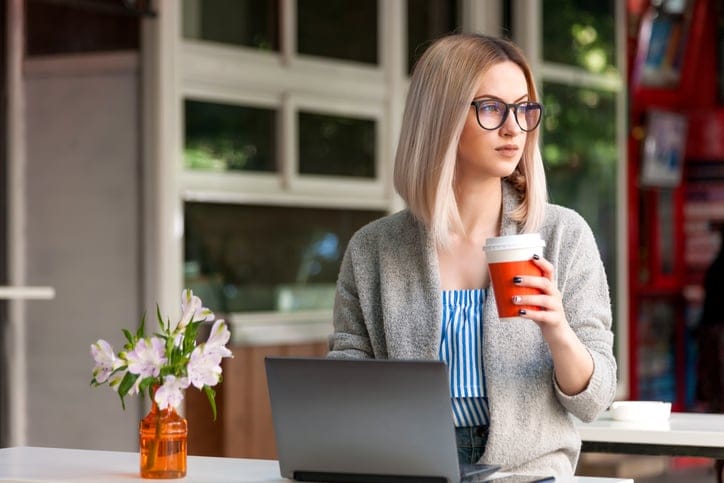 Attractive woman with laptop outdoors in cafe