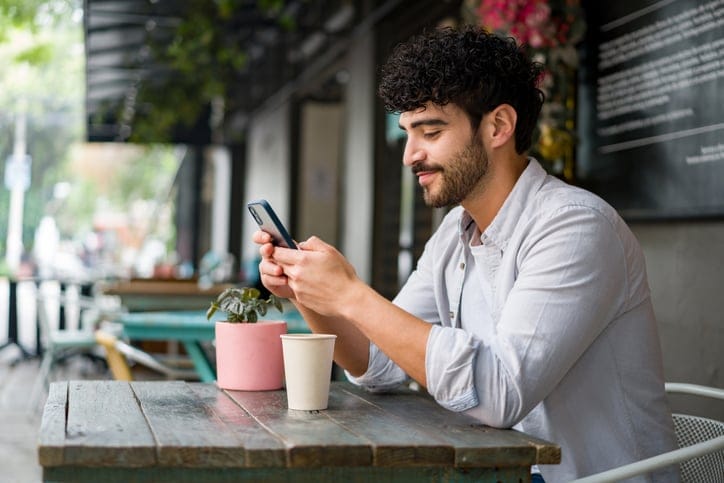 guy texting at outdoor cafe