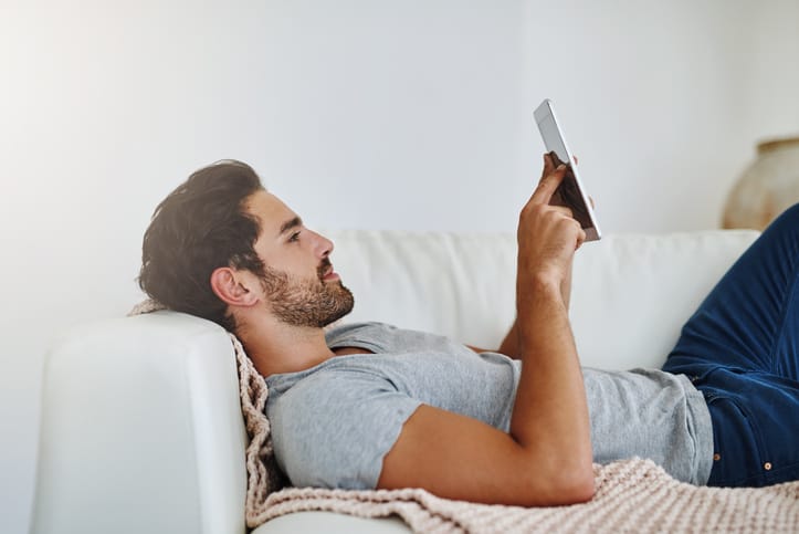 Man laying on the couch on his phone.