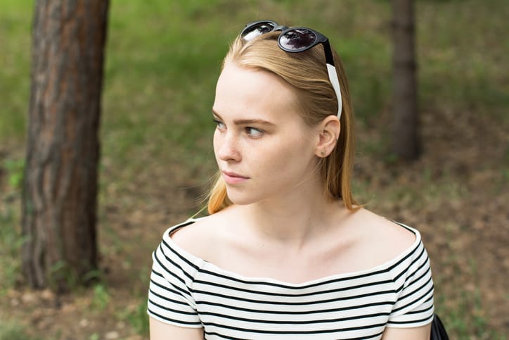 Portrait of a pensive young woman looking away. A woman in a striped dress on a background of nature