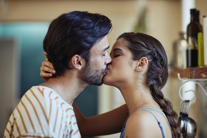 Shot of an affectionate young couple kissing in their kitchen at home