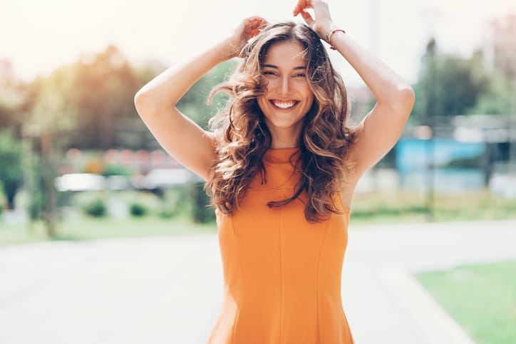 Beautiful young woman dancing outdoors on a sunny day