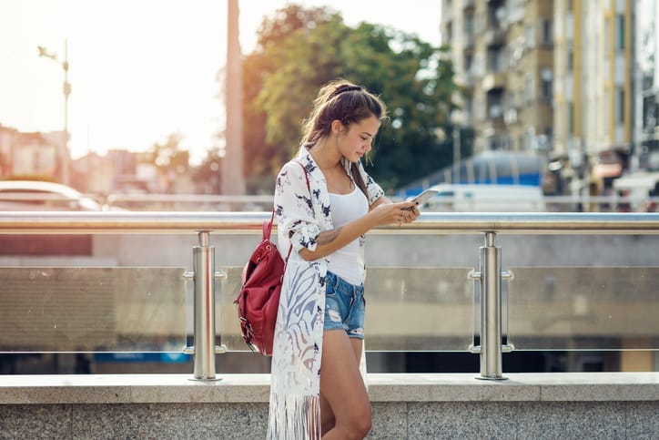 young trendy woman texting in the street