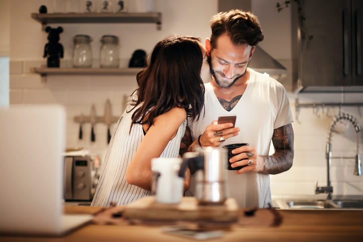 Young couple at home using smartphone - Morning breakfast time