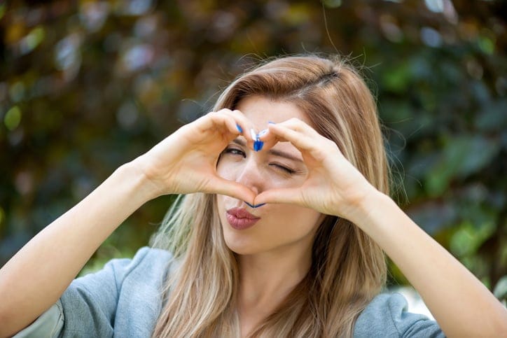 Young woman doing a heart with her hands.